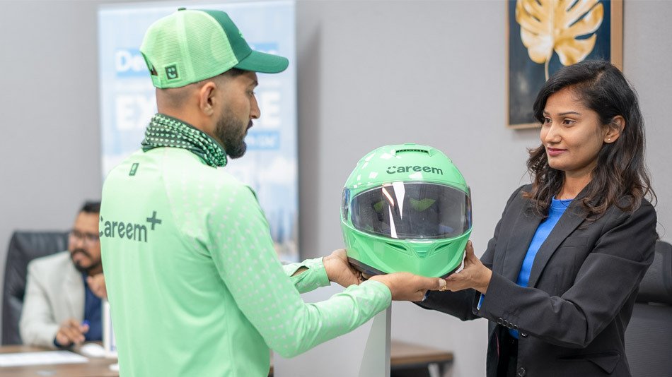 Emirates Way Delivery Services Operation team member giving Careem helmet to Careem rider