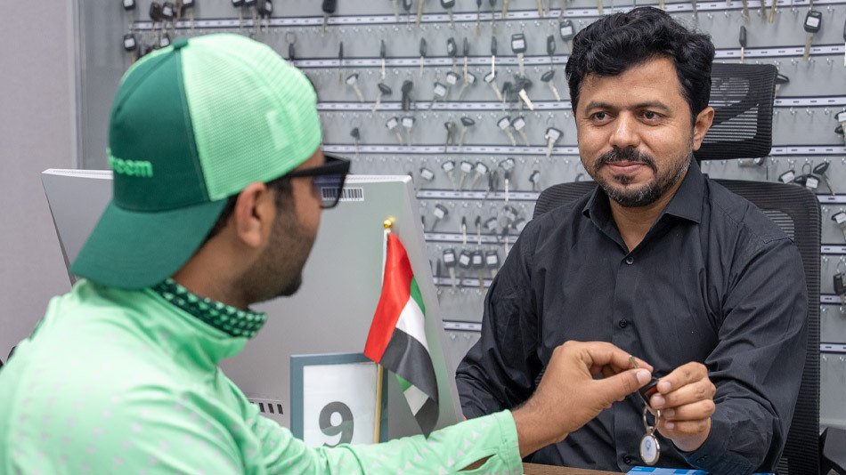 Emirates Way Delivery Services Employee Presenting Bike Key to Rider