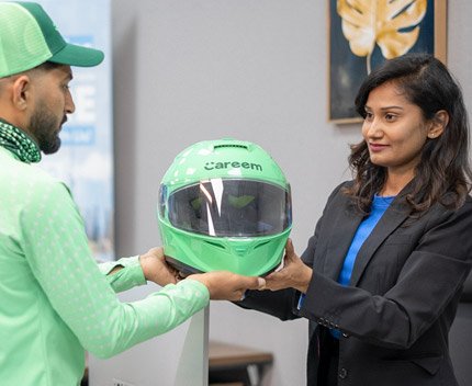 Emirates Way Delivery Services Operations Team Member Presenting Helmet to Careem Rider