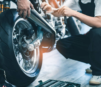 Emirates Way Delivery Services auto garage mechanic working on exhaust of bike